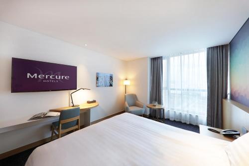 a hotel room with a bed and a desk at Mercure Ambassador Ulsan in Ulsan