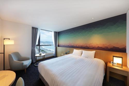 a hotel room with a bed and a desk and a chair at Mercure Ambassador Ulsan in Ulsan