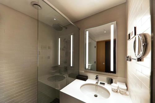 a bathroom with a sink and a shower and a mirror at Mercure Ambassador Ulsan in Ulsan