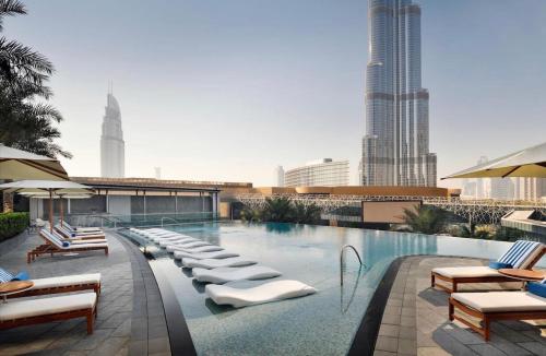 a swimming pool with lounge chairs and a city skyline at 2 Bedroom with Full Burj view in Dubai