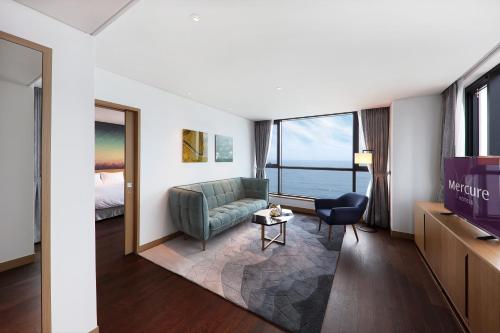a hotel room with a couch and a bed at Mercure Ambassador Ulsan in Ulsan