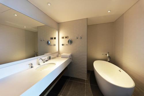 a bathroom with two sinks and a tub and a large mirror at Mercure Ambassador Ulsan in Ulsan