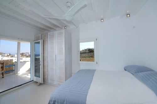 a white bedroom with a bed and a balcony at Luxury White Maisonette in Kalafatis