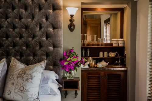 um quarto com uma grande cabeceira acolchoada e um lavatório em Schoone Oordt Country House em Swellendam