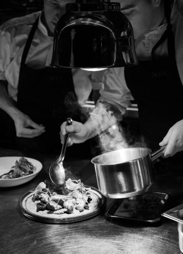 a person preparing a pizza in a kitchen at At Six in Stockholm