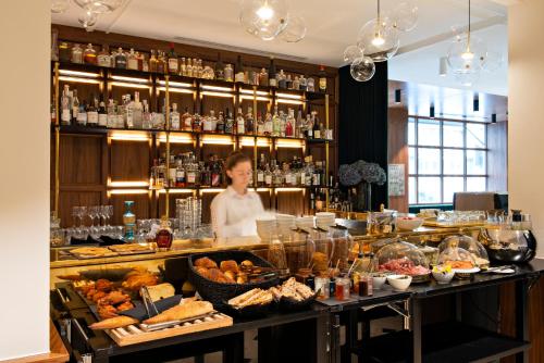 a woman behind a counter with a buffet of food at Hotel Parister & Spa in Paris