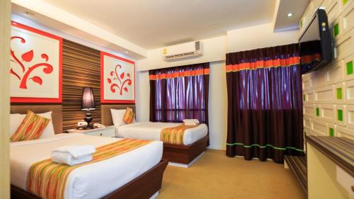 a hotel room with two beds and a flat screen tv at Kwan Ruen Park in Nakhon Ratchasima