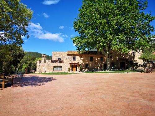 a large stone building with a tree in the foreground at Mas del Sord 1335 in La Selva del Camp