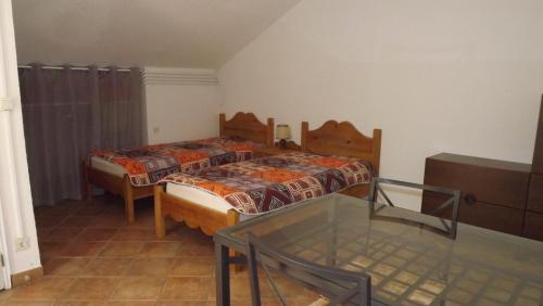 a bedroom with two beds and a glass table at Lou Pichoun Jas in Cavaillon