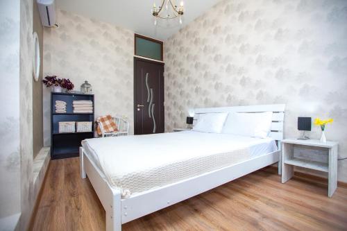 a bedroom with a white bed and a wall at Lebu Apartment TBS in Tbilisi City