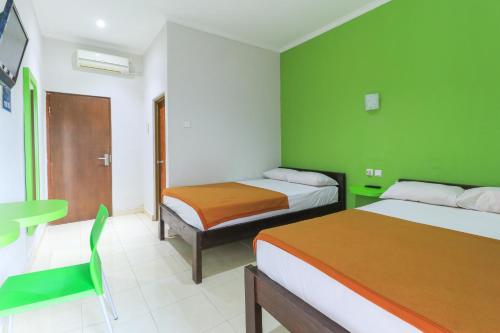 a room with two beds and a green wall at Hotel Warta Putra in Denpasar