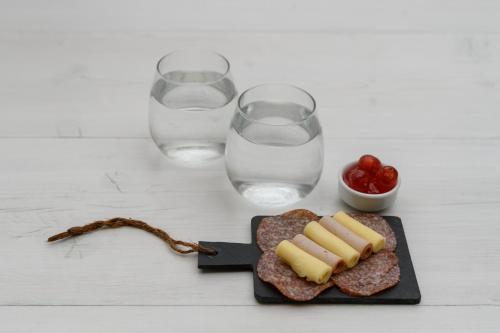a plate of food with glasses of water and some meat at Cova Mykonos Suites in Elia Beach