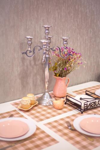 a table with plates and a vase with flowers on it at Lebu Apartment TBS in Tbilisi City