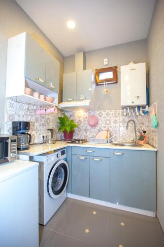 a kitchen with blue cabinets and a washer and dryer at Lebu Apartment TBS in Tbilisi City