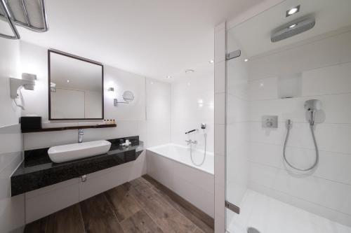 アムステルダムにあるビルダーバーグ ガーデン ホテルの白いバスルーム(シンク、シャワー付)
