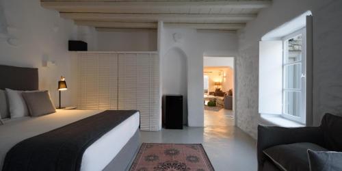 a bedroom with a white bed and white walls at Cova Mykonos Suites in Elia Beach