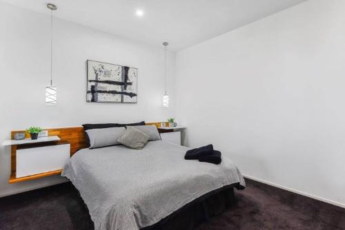 a white bedroom with a bed and a table at BENGALEE EXECUTIVE TOWNHOUSE- MODERN & STYLISH in Mount Gambier