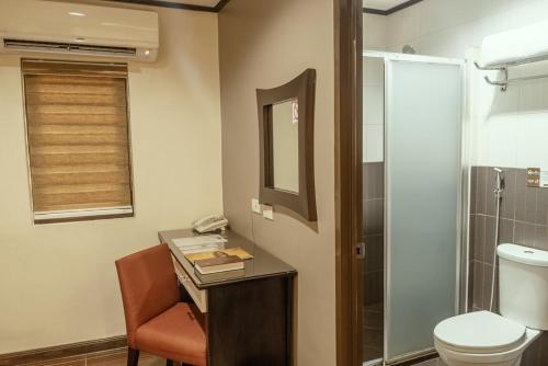 a bathroom with a toilet and a desk with a phone at Casa Bocobo Hotel in Manila