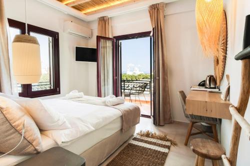 a bedroom with a bed and a desk and a window at Aktaion Beach Boutique Hotel & Spa in Skala