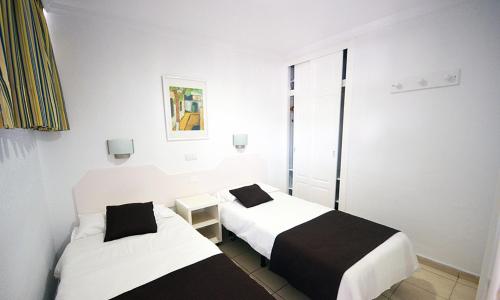 two beds in a room with white walls at Apartamentos Arco Iris in Playa del Ingles
