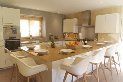 une cuisine avec une grande table en bois et des chaises blanches dans l'établissement Domaine St Gilles - Proche activités aquatiques et équestres, à Baurech