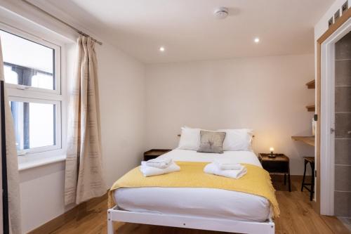 a bedroom with a bed with towels on it at Weeping Willow – Three Tuns Apartments, Pettistree in Pettistree