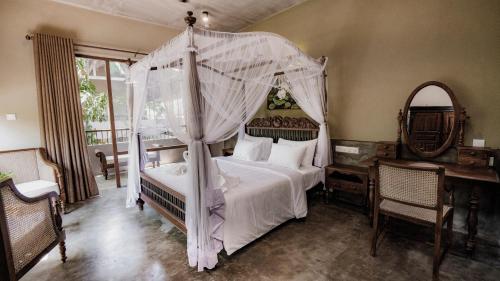 a bedroom with a canopy bed and a desk at Ayur Ayur Resort & Ayurveda Retreat in Negombo