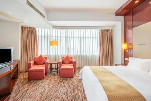 a hotel room with a bed and two chairs and a television at Holiday Inn Xiaoshan by IHG in Hangzhou