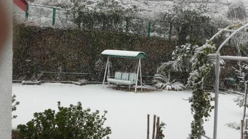 a snow covered garden with a bench and a gazebo at Rosewood Estate in Chail