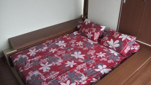 a bed with red and white flowers on it at Ruby Apartment #2 in Yogyakarta