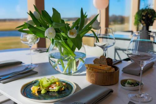 a table with a plate of food and a vase of flowers at Jurmala Golf Club&Hotel in Piņķi