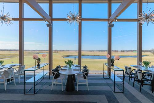 a dining room with tables and chairs and large windows at Jurmala Golf Club&Hotel in Piņķi