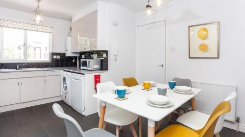 a white kitchen with a white table and chairs at Malt Shovel Court with Free Parking in York