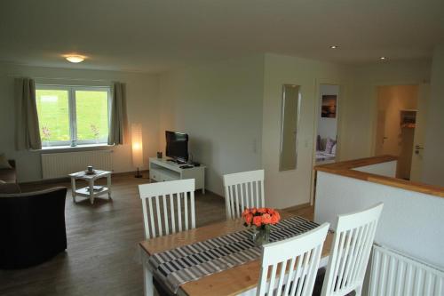 a living room with a table and white chairs at Haus am Meer in Vollerwiek