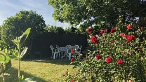 a garden with a table and chairs and red roses at Haus am Meer in Vollerwiek