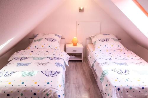 two twin beds in a attic bedroom with a lamp at Ferienwohnungen Hoffmann in Garding