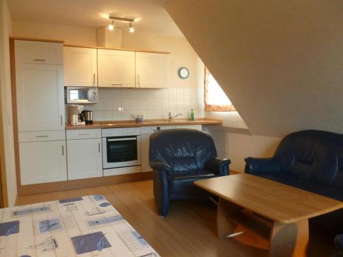 a living room with two chairs and a table and a kitchen at Hof Peters in Tating