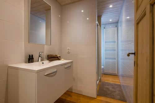 a white bathroom with a sink and a shower at Maison Mariette in Nieuwpoort