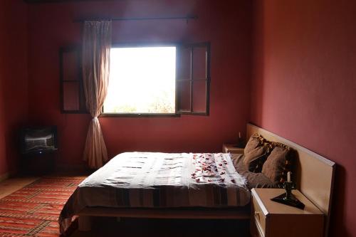 a red bedroom with a bed and a window at Villa Paradise in Aghmat