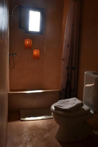 a bathroom with a toilet and a tub and a window at Villa Paradise in Aghmat