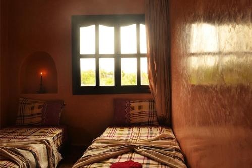 a bedroom with two beds and a window at Villa Paradise in Aghmat