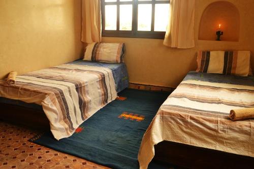 a room with two beds and a window at Villa Paradise in Aghmat