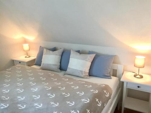 Schlafzimmer mit einem Bett mit blauen und weißen Kissen in der Unterkunft Haus Wattläufer - Lütte Koje in Sankt Peter-Ording