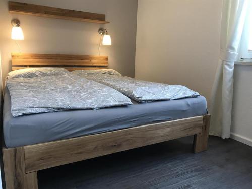 a bed with a wooden headboard and blue sheets at Diekje Deel in Sankt Peter-Ording