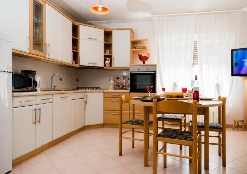 Apartment Dora في أوماغ: مطبخ مع دواليب بيضاء وطاولة وكراسي