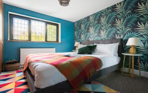 a bedroom with blue walls and a bed with a colorful blanket at The Madras Cottage - Bright 3BDR Home with Garden in Cambridge