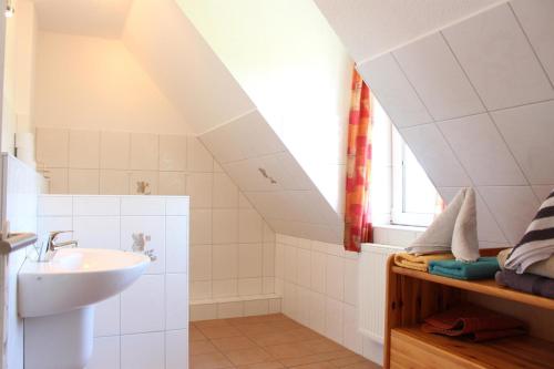 a white bathroom with a sink and a window at Bauernhof Rickerts in Vollerwiek