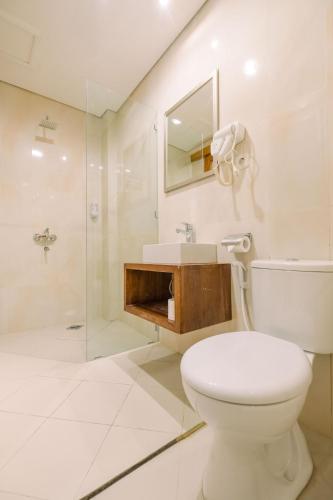 a bathroom with a toilet and a sink and a shower at Caroline Guest House in Canggu