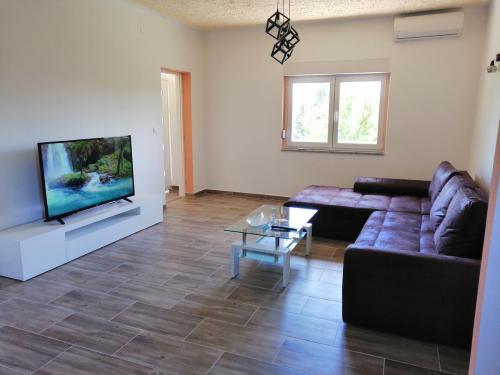 a living room with a couch and a flat screen tv at Holiday House Ivan in Donji Zemunik
