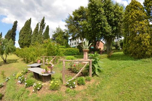 a garden with a bench and flowers in the grass at Villa al Borghetto in Uzzano